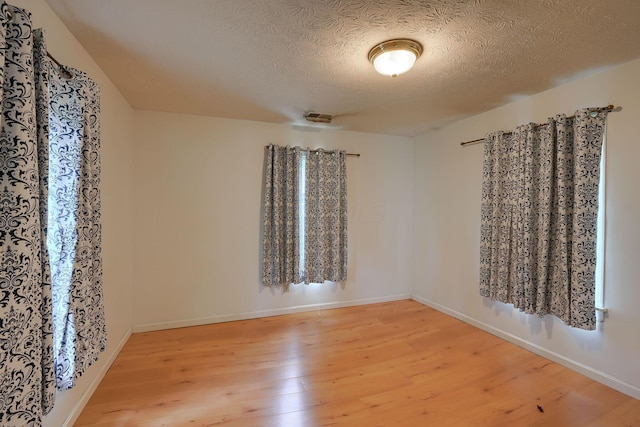 unfurnished room with a textured ceiling and light hardwood / wood-style flooring