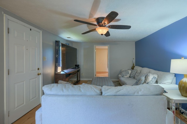 living room with ceiling fan, a textured ceiling, and light hardwood / wood-style flooring