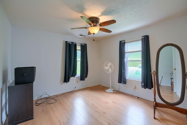 spare room featuring a textured ceiling, light hardwood / wood-style flooring, and ceiling fan