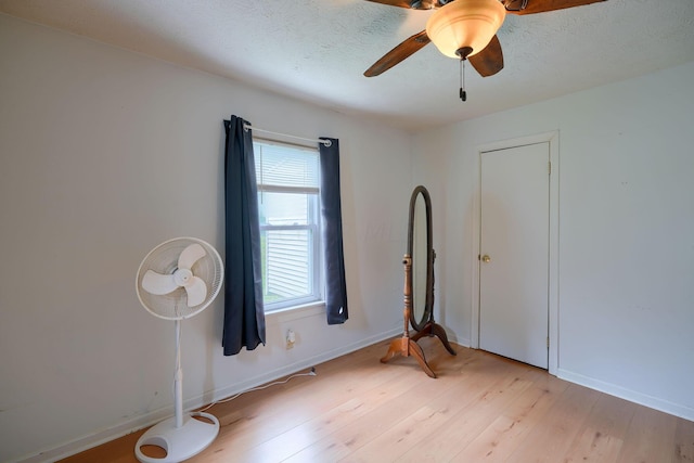 empty room featuring ceiling fan, a textured ceiling, and light hardwood / wood-style flooring