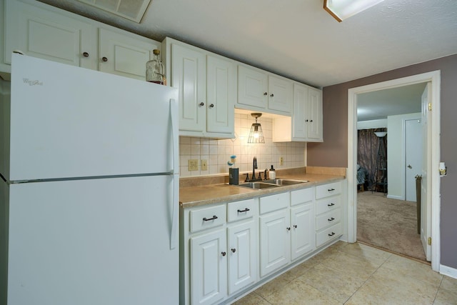 kitchen featuring white cabinets, light tile patterned floors, white fridge, and sink