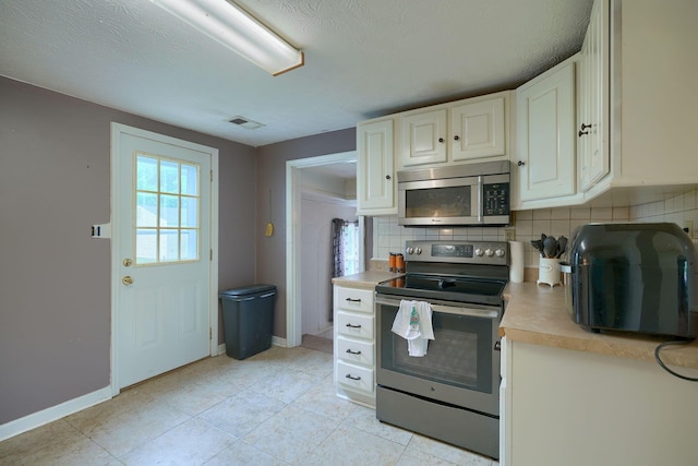 kitchen featuring light tile patterned floors, a textured ceiling, appliances with stainless steel finishes, and tasteful backsplash