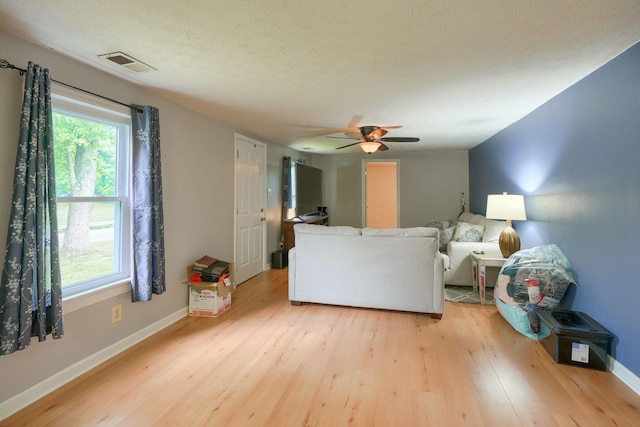 living room featuring a textured ceiling, light hardwood / wood-style flooring, and ceiling fan