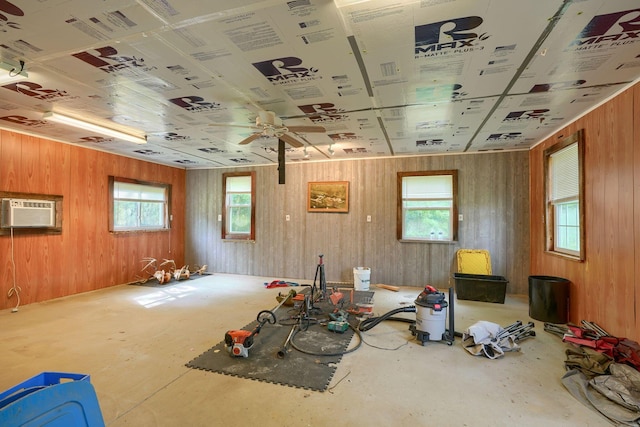 misc room with an AC wall unit, wood walls, plenty of natural light, and ceiling fan