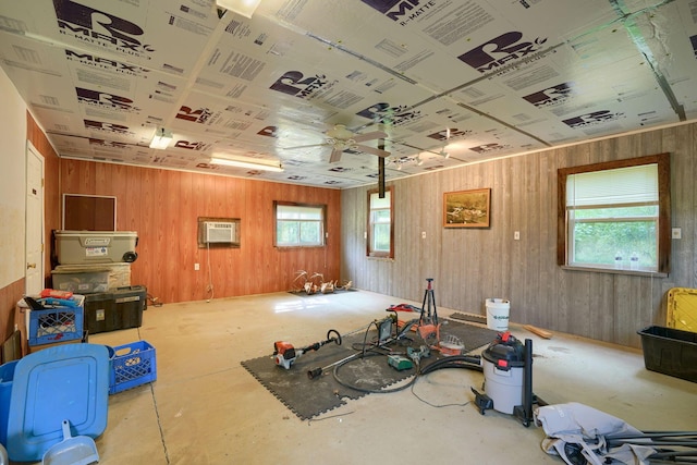 miscellaneous room featuring a wall unit AC, a wealth of natural light, ceiling fan, and wood walls