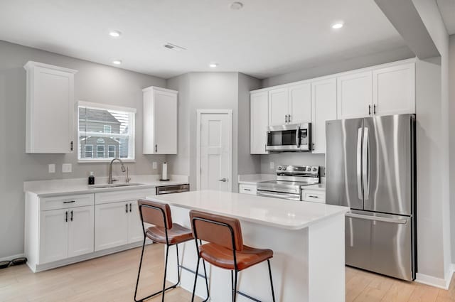 kitchen with a center island, sink, white cabinetry, and stainless steel appliances