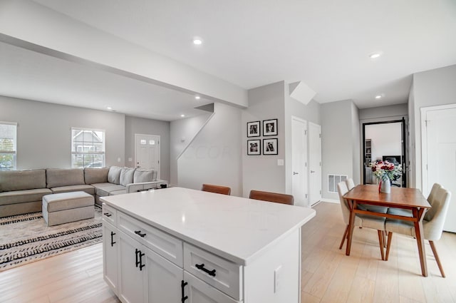 kitchen with light hardwood / wood-style flooring, a kitchen island, and white cabinetry