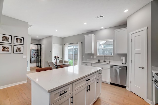 kitchen featuring white cabinets, sink, light hardwood / wood-style flooring, stainless steel dishwasher, and a kitchen island