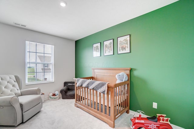 carpeted bedroom featuring a nursery area