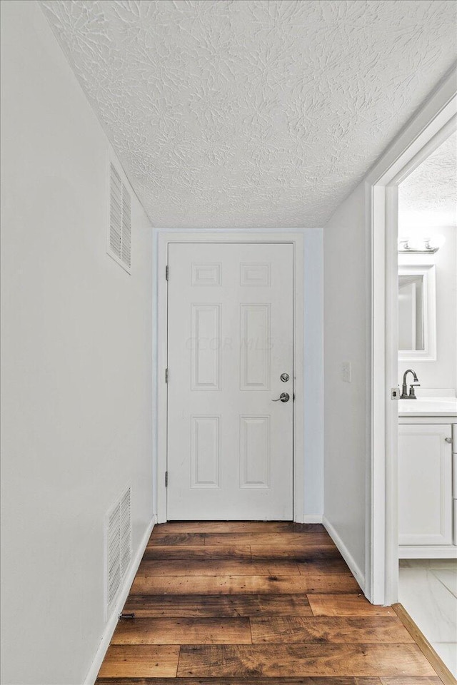 doorway with a textured ceiling, dark hardwood / wood-style floors, and sink