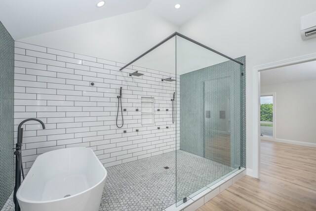 bathroom with plus walk in shower, hardwood / wood-style floors, a wall mounted air conditioner, and vaulted ceiling