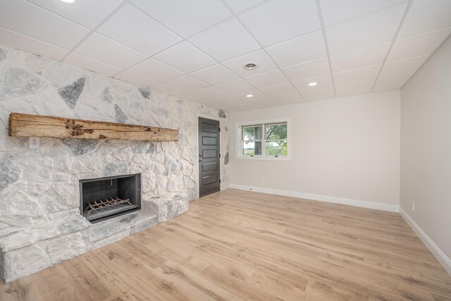 unfurnished living room with hardwood / wood-style floors, a drop ceiling, and a fireplace