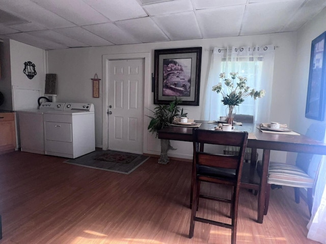 dining area with a paneled ceiling, washer and clothes dryer, and hardwood / wood-style floors