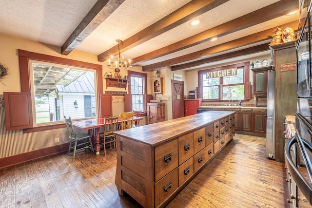 kitchen with decorative light fixtures, a textured ceiling, hardwood / wood-style flooring, and a notable chandelier