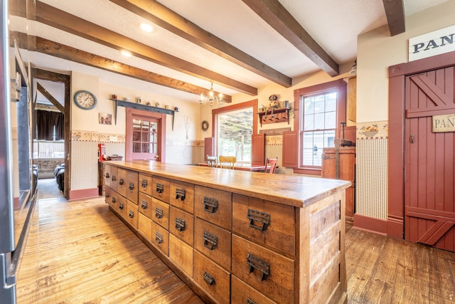 kitchen with a center island, an inviting chandelier, light hardwood / wood-style flooring, butcher block countertops, and beam ceiling