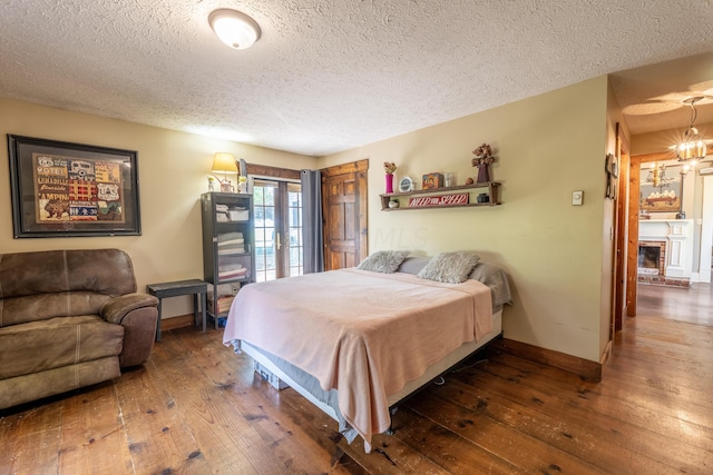 bedroom featuring dark hardwood / wood-style flooring, a textured ceiling, and a chandelier