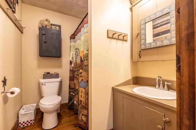 bathroom with walk in shower, vanity, a textured ceiling, hardwood / wood-style flooring, and toilet