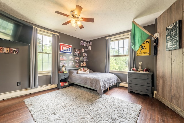 bedroom featuring dark hardwood / wood-style flooring, ceiling fan, and wood walls