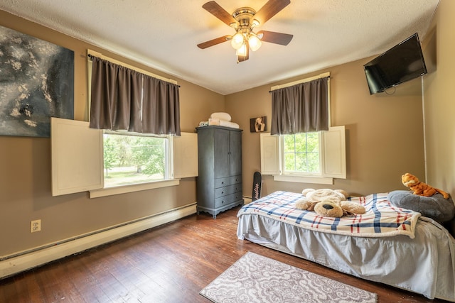 bedroom featuring multiple windows, ceiling fan, hardwood / wood-style floors, and a baseboard radiator