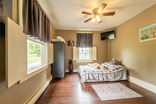 bedroom with ceiling fan, dark wood-type flooring, a baseboard radiator, and multiple windows