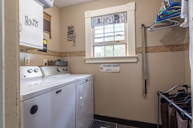 laundry area featuring cabinets, a textured ceiling, and washing machine and clothes dryer