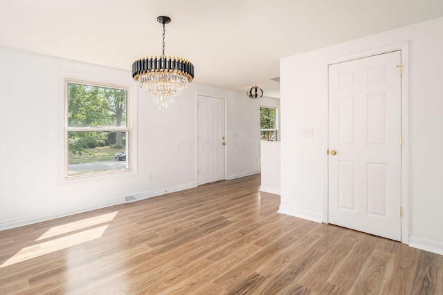 interior space featuring light wood-type flooring, a wealth of natural light, and an inviting chandelier