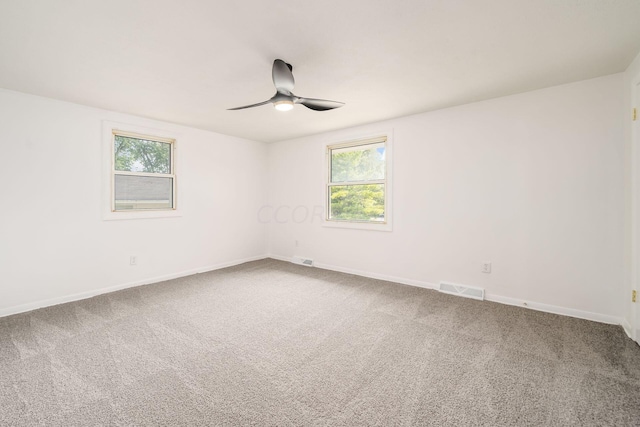 spare room featuring carpet flooring, ceiling fan, and a wealth of natural light