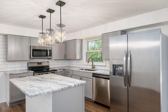 kitchen featuring a center island, sink, dark hardwood / wood-style floors, light stone countertops, and stainless steel appliances