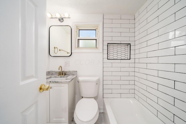 full bathroom with a textured ceiling, vanity, toilet, and tiled shower / bath