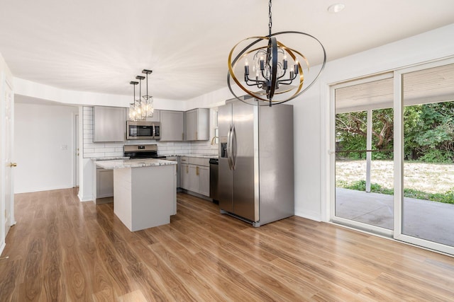 kitchen with a center island, hanging light fixtures, light hardwood / wood-style flooring, gray cabinets, and appliances with stainless steel finishes