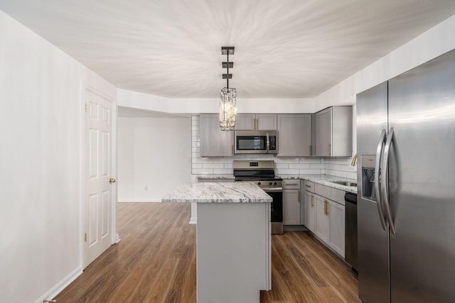 kitchen featuring gray cabinetry, a center island, stainless steel appliances, and hanging light fixtures