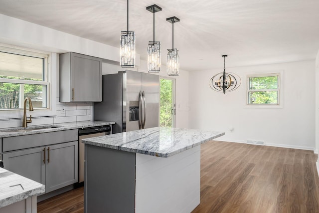 kitchen with appliances with stainless steel finishes, hanging light fixtures, gray cabinetry, and sink