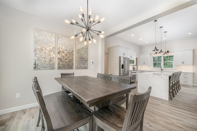 dining area with a notable chandelier, light wood-type flooring, and sink