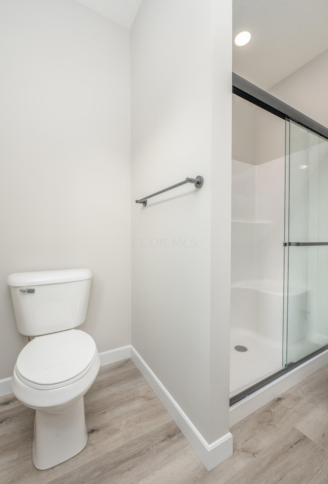 bathroom featuring a shower with door, wood-type flooring, and toilet