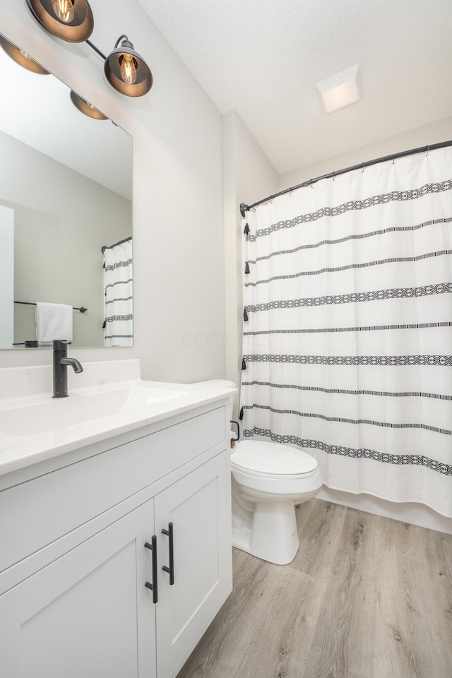 bathroom with toilet, vanity, and hardwood / wood-style flooring