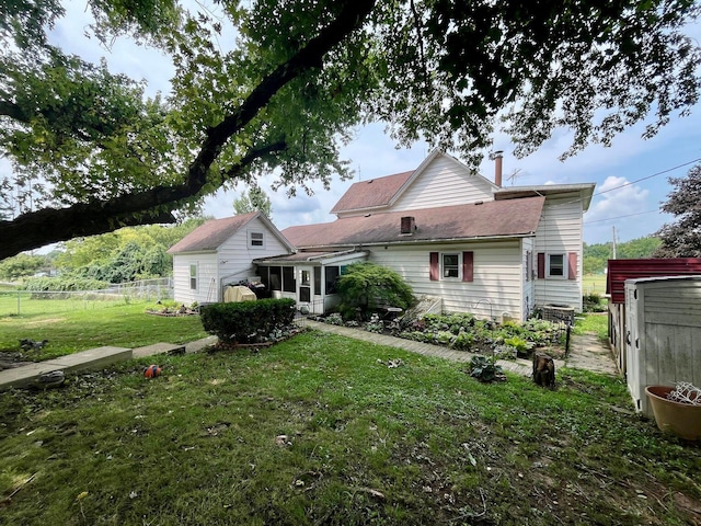 back of property featuring a sunroom, a yard, and an outdoor structure