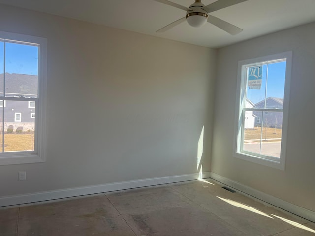 unfurnished room with ceiling fan, concrete floors, visible vents, and baseboards