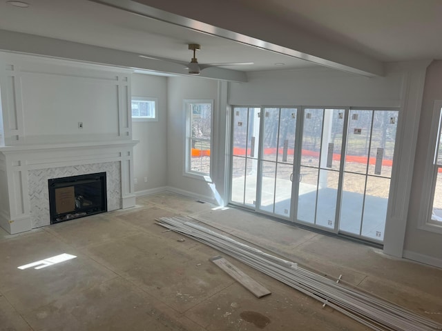 unfurnished living room with ceiling fan, baseboards, a tiled fireplace, and beamed ceiling