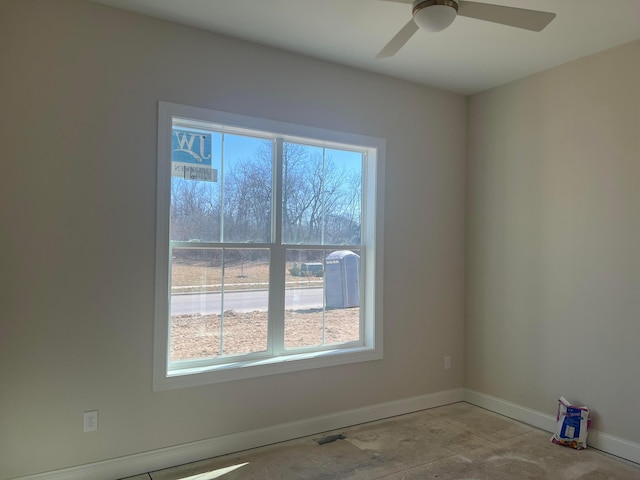 spare room with a ceiling fan, concrete floors, and baseboards