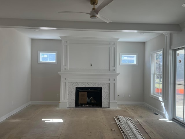 unfurnished living room with ceiling fan, baseboards, and a tiled fireplace