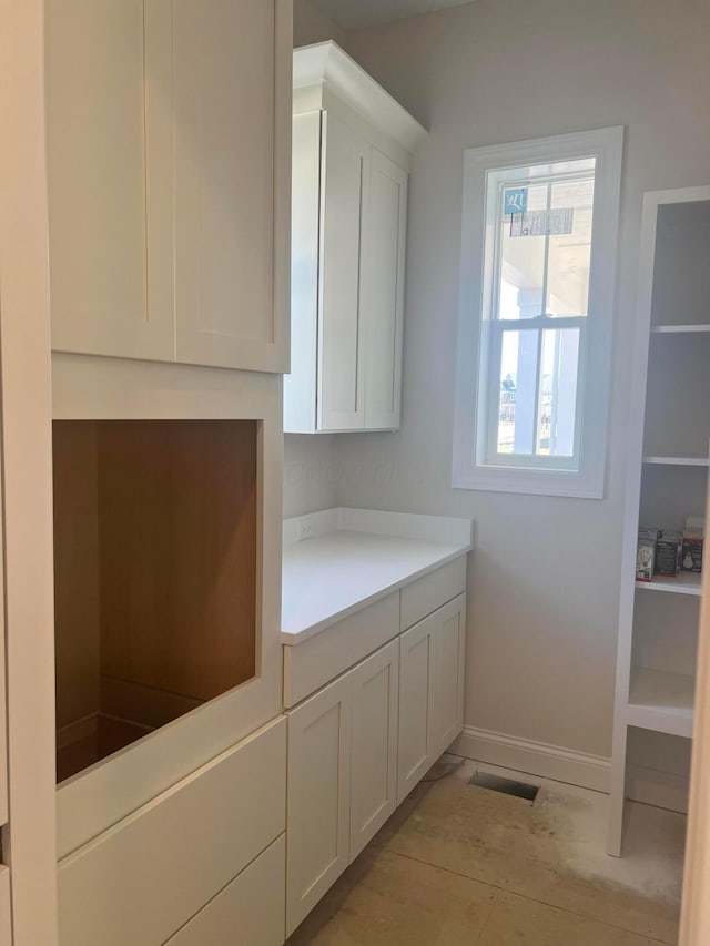 interior space featuring light countertops, white cabinetry, and baseboards