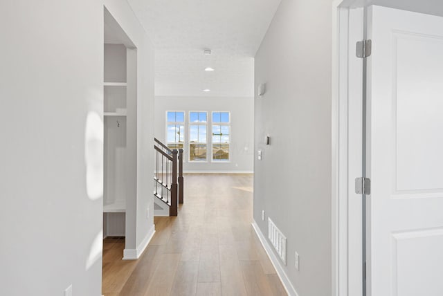 hallway with light wood-type flooring and a textured ceiling