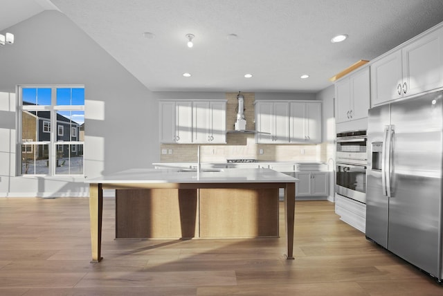 kitchen with white cabinetry, stainless steel appliances, tasteful backsplash, wall chimney exhaust hood, and a breakfast bar