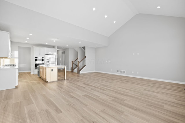 unfurnished living room with high vaulted ceiling and light hardwood / wood-style floors