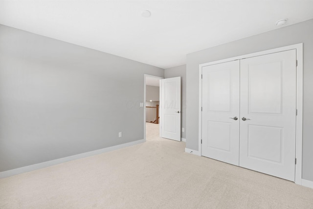 unfurnished bedroom with light carpet and a closet