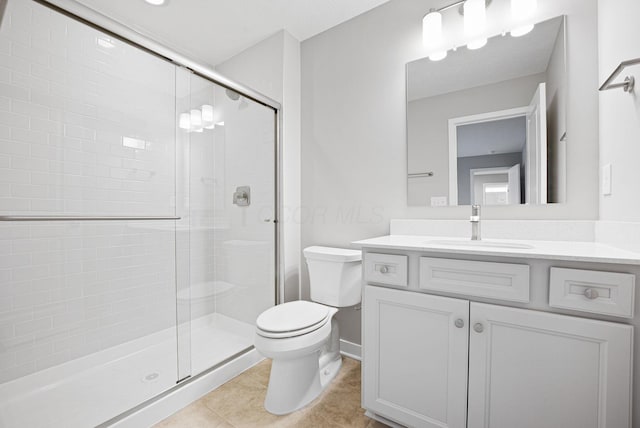 bathroom with vanity, tile patterned flooring, a shower with door, and toilet