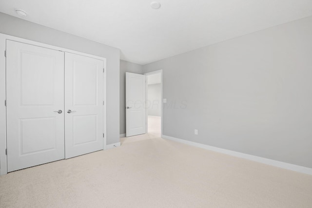 unfurnished bedroom with light carpet and a closet