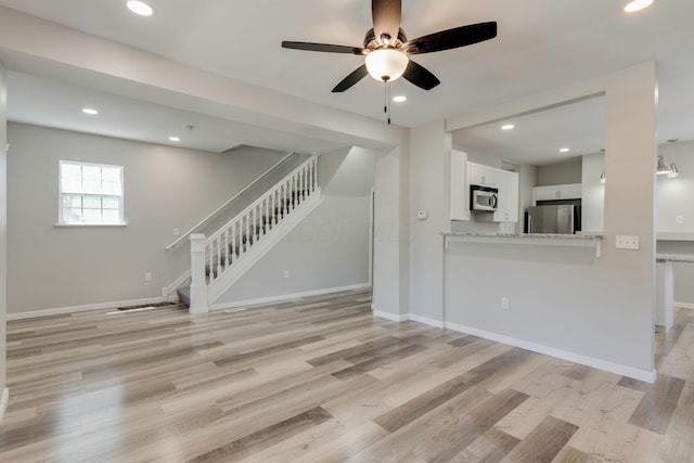 unfurnished living room featuring ceiling fan and light wood-type flooring