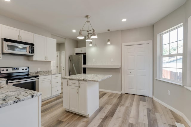 kitchen with pendant lighting, white cabinets, light wood-type flooring, and appliances with stainless steel finishes