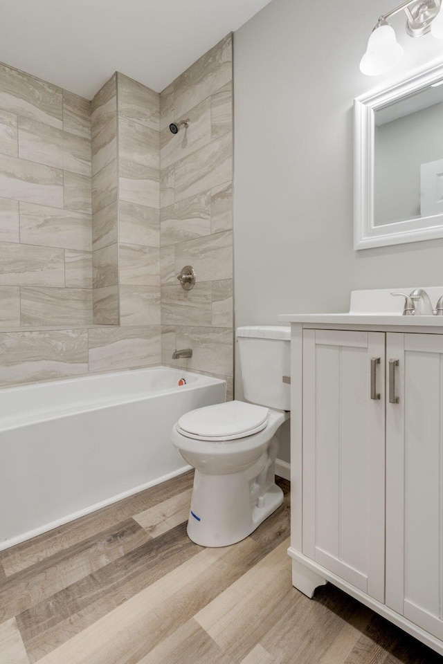 full bathroom featuring hardwood / wood-style floors, vanity, tiled shower / bath combo, and toilet